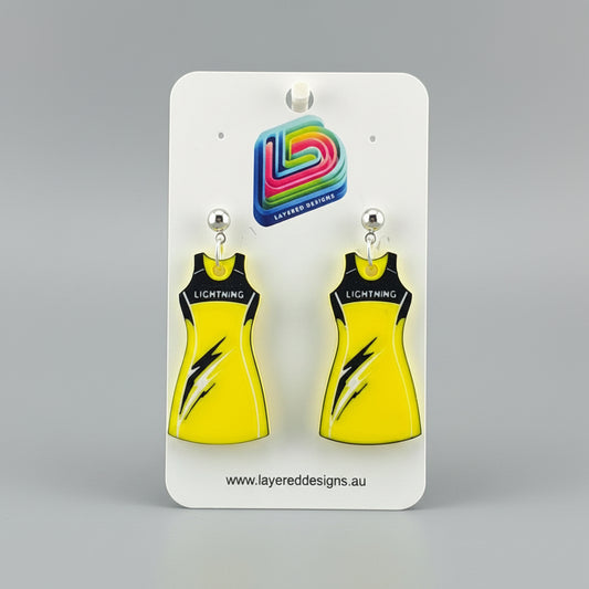Yellow dress-shaped earrings on a stand with a branded card in the background