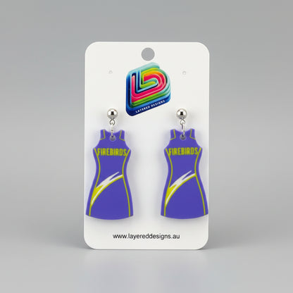 Pair of purple dress-shaped earrings on a Layered Designs card with a gray background