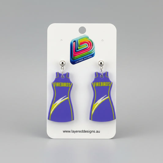 Pair of purple dress-shaped earrings on a Layered Designs card with a gray background