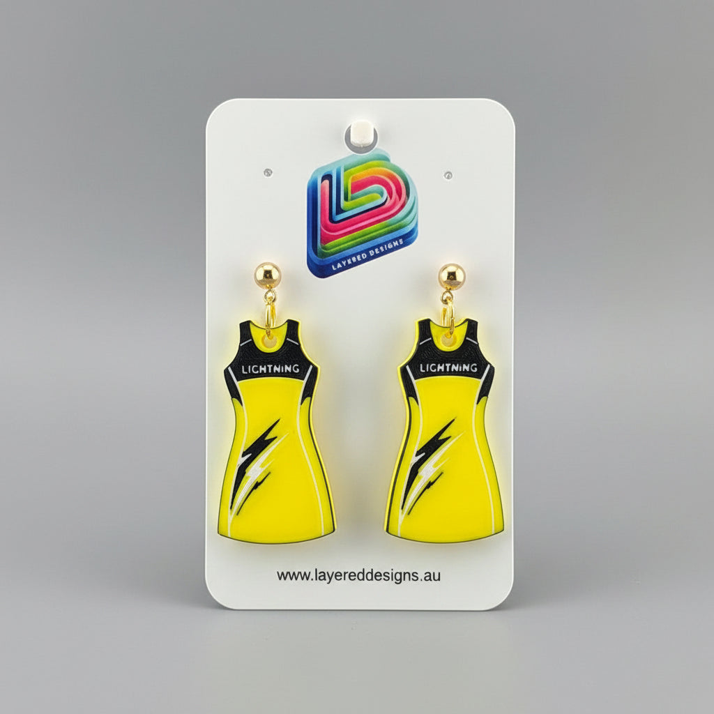 Yellow dress-shaped earrings on a stand with a branded card in the background