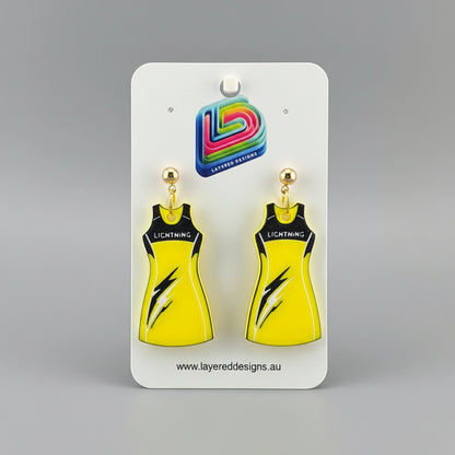 Yellow dress-shaped earrings on a stand with a branded card in the background