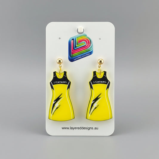 Yellow dress-shaped earrings on a stand with a branded card in the background